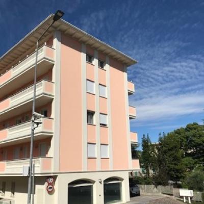 Edificio rosa a più piani con garage e cielo sereno.